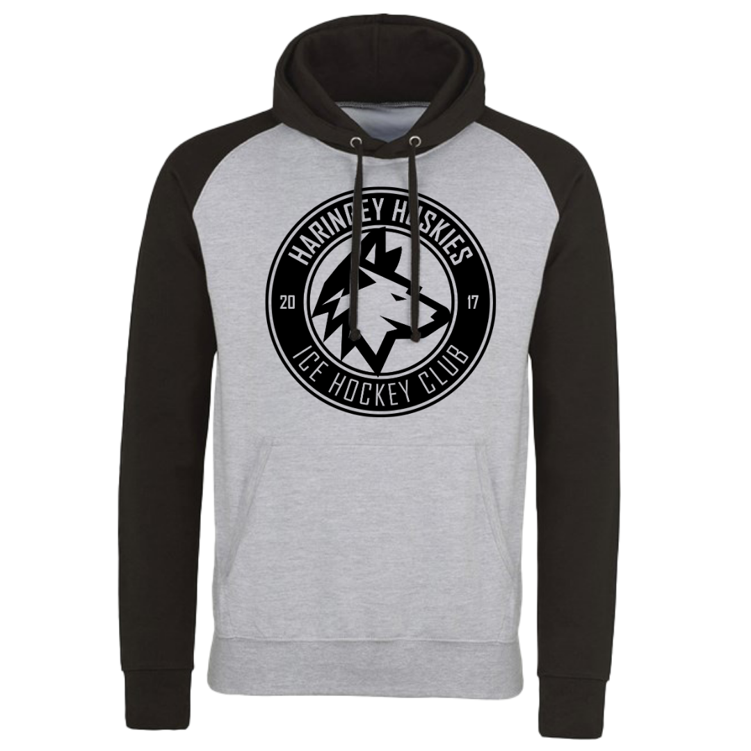 The Haringey Huskies Stores Huskies Baseball Hoodie Black/Grey features black sleeves and hood, a light gray body, and a chest circular logo with Haringey Huskies Ice Hockey Club 2017—ideal for streetwear fans.