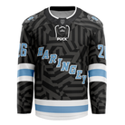 Introducing the Haringey Huskies 26/27 Away Jersey (NAMED) from the Haringey Huskies Store—a black hockey jersey featuring bold geometric patterns, light blue and white stripes on the arms and waist, "HARINGEY" in light blue letters across the chest, and the number 26 on both sleeves. Available as a Fan Replica Jersey, you can personalize it with your own custom name and number for a unique touch.
