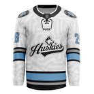 The Haringey Huskies 26/27 Home Jersey (NAMED) from the Haringey Huskies Store showcases a crisp white design accented with light blue and black stripes. Bold "Huskies" text and the iconic husky dog logo feature prominently on the chest, while the number 26 appears on both sleeves and circular patches decorate each shoulder. As a fan replica jersey, it can also be personalized with your choice of custom name and number for an extra-special touch.